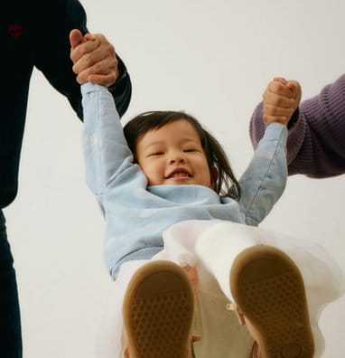 A toddler smiling with arms raised